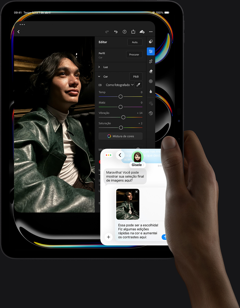 Parte da frente do iPad Pro preto-espacial na vertical. A mão direita segura o aparelho. A tela mostra um app de edição de fotos com a imagem de uma pessoa com jaqueta de couro, ferramentas e controles de edição, uma conversa do iMessage entre o usuário e outra pessoa revisando a foto