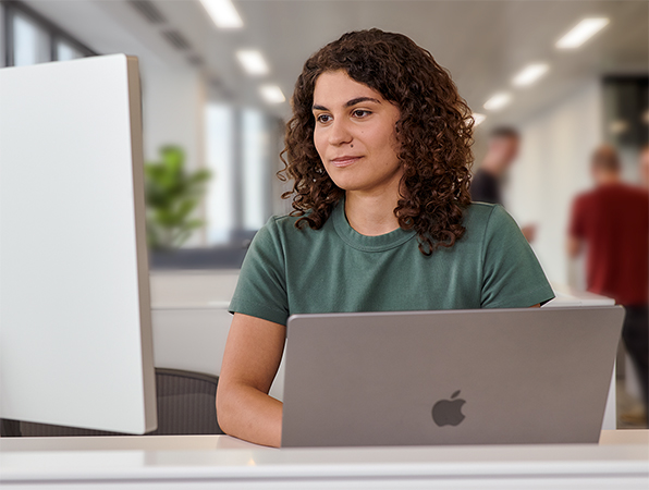 موظفة من فريق Apple تستخدم MacBook وشاشة Studio Display في مكتب.