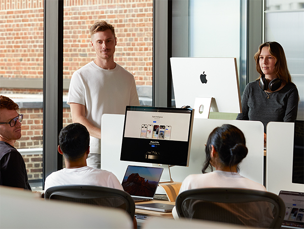 خمسة من الزملاء العاملين في شركة Apple مجتمعين حول مكاتبهم للمشاركة في المحادثة.