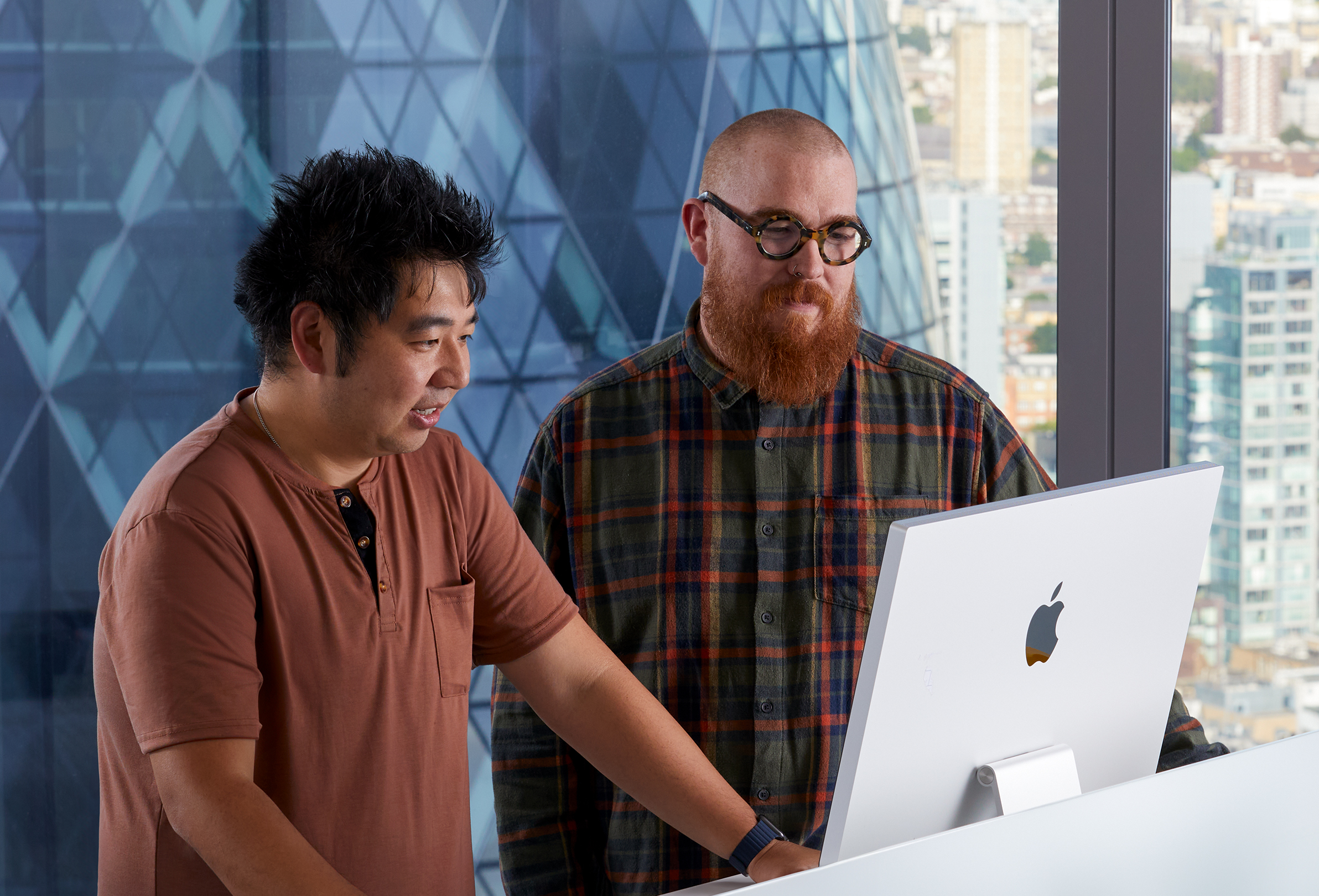 زميلان في شركة Apple يتعاونان أثناء استخدام جهاز iMac.