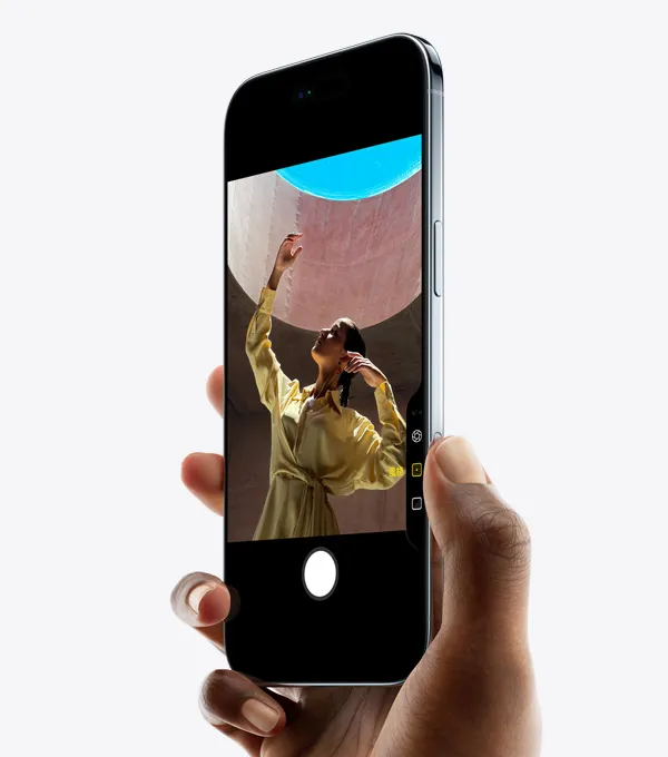 一隻手握著 iPhone Air，拇指按著相機控制按鈕，機身正面側斜擺放，展示纖薄外型、動態島、側邊按鈕