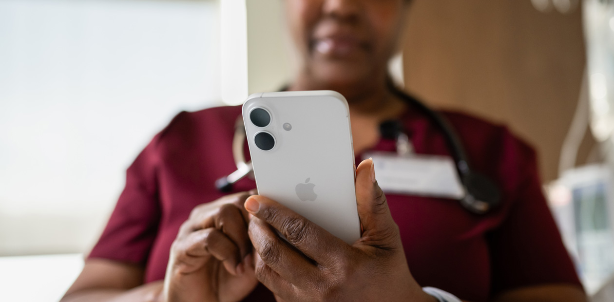 赤いスクラブを着た女性看護師がiPhoneを見ている