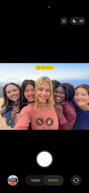 Aplikace Fotoaparát na iPhonu 17 Pro, centrování záběru pro fotky při focení selfie se skupinou lidí, jejichž obličeje jsou zvýrazněné Aplikace Fotoaparát na iPhonu 17 Pro, centrování záběru pro fotky při focení selfie se skupinou lidí, jejichž obličeje jsou zvýrazněné